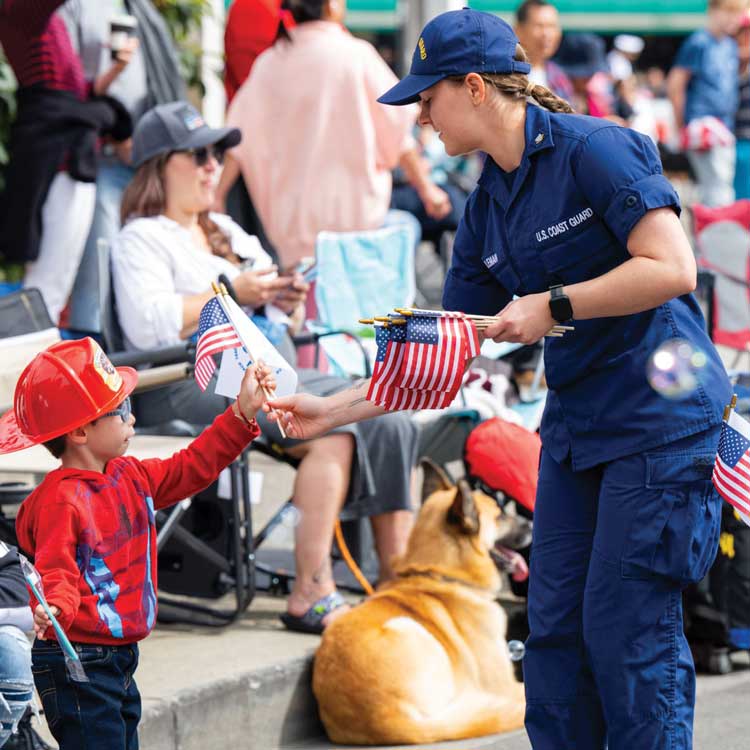 servicemember handing out flag to little boy